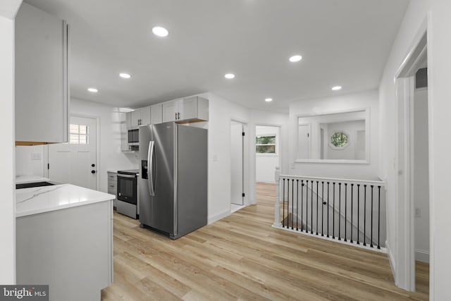 kitchen with stainless steel appliances, recessed lighting, light wood-style floors, white cabinets, and baseboards