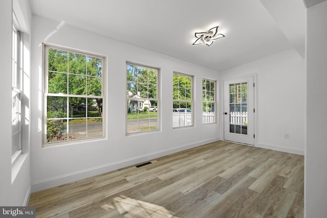 unfurnished sunroom featuring visible vents and vaulted ceiling