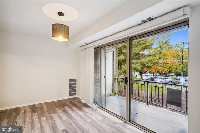 doorway to outside with plenty of natural light, wood finished floors, visible vents, and baseboards