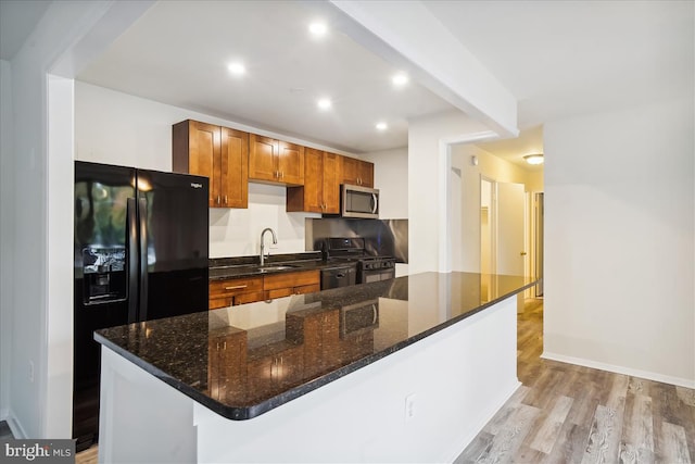 kitchen with brown cabinetry, light wood-style flooring, black appliances, a sink, and recessed lighting