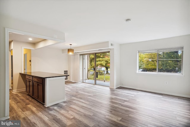 kitchen featuring light wood-type flooring, dark countertops, pendant lighting, and plenty of natural light