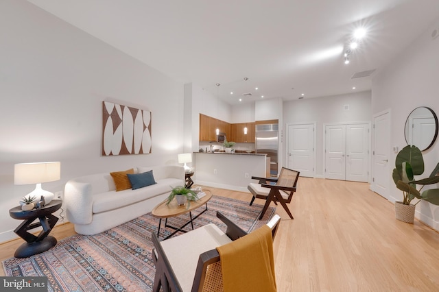 living room with recessed lighting, visible vents, baseboards, and light wood finished floors