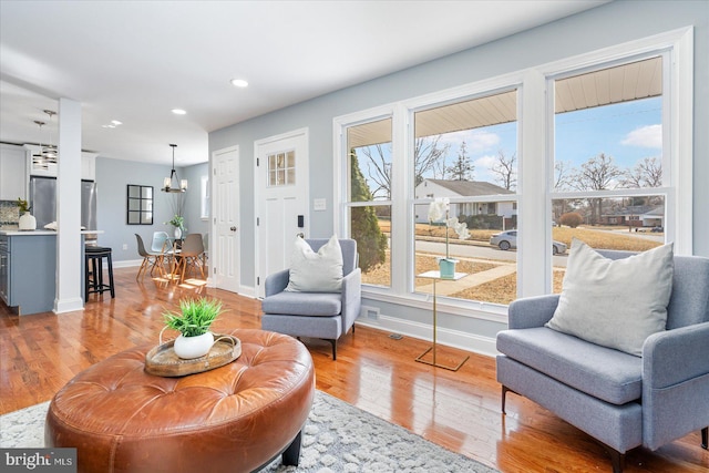 living area with a chandelier, recessed lighting, baseboards, and wood finished floors