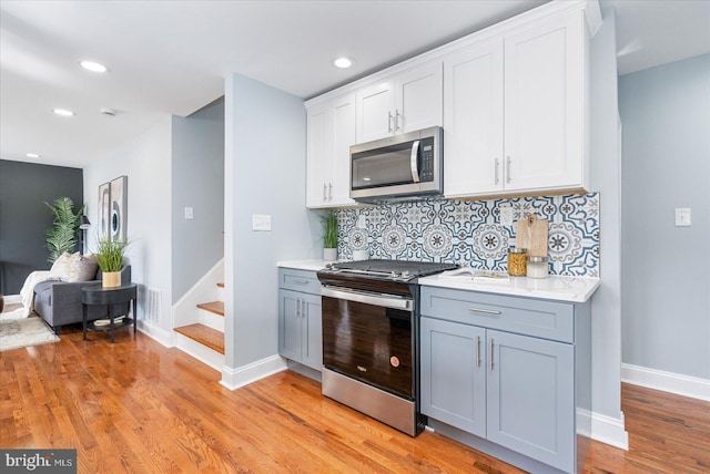 kitchen with light wood-style floors, tasteful backsplash, appliances with stainless steel finishes, and light countertops