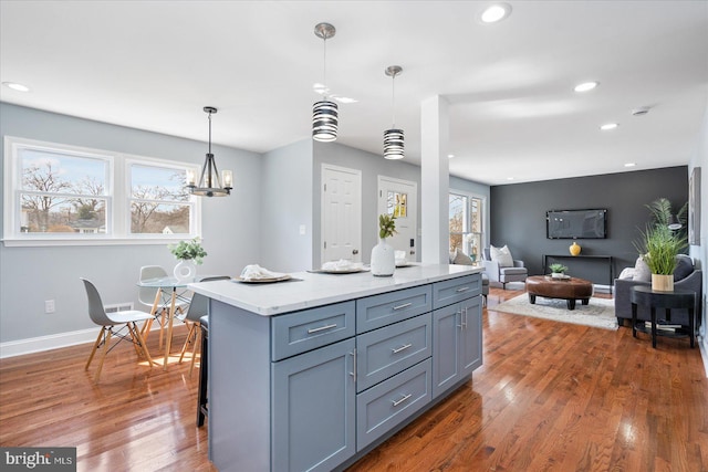 kitchen featuring recessed lighting, a kitchen island, wood finished floors, gray cabinets, and pendant lighting