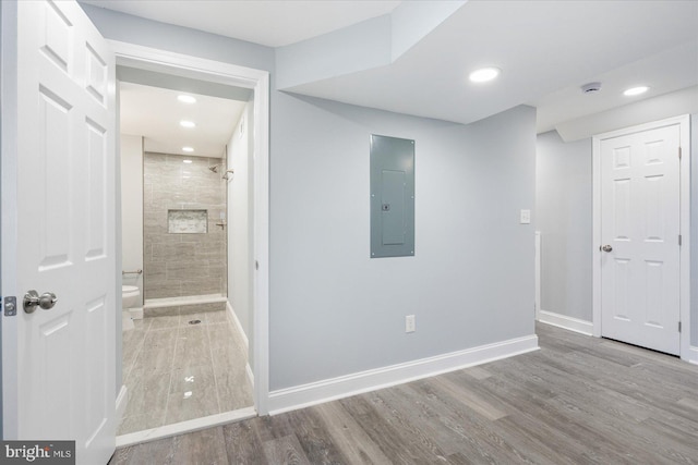 empty room featuring recessed lighting, electric panel, baseboards, and wood finished floors