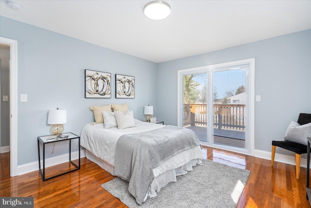 bedroom featuring access to outside, wood finished floors, and baseboards