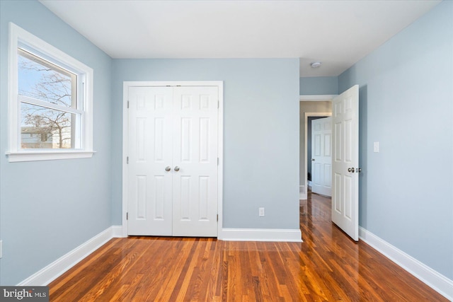 unfurnished bedroom with a closet, baseboards, and wood finished floors