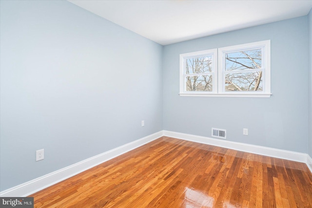 unfurnished room with baseboards, visible vents, and wood finished floors