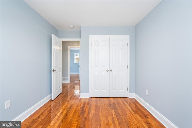 unfurnished bedroom featuring a closet, baseboards, and wood finished floors