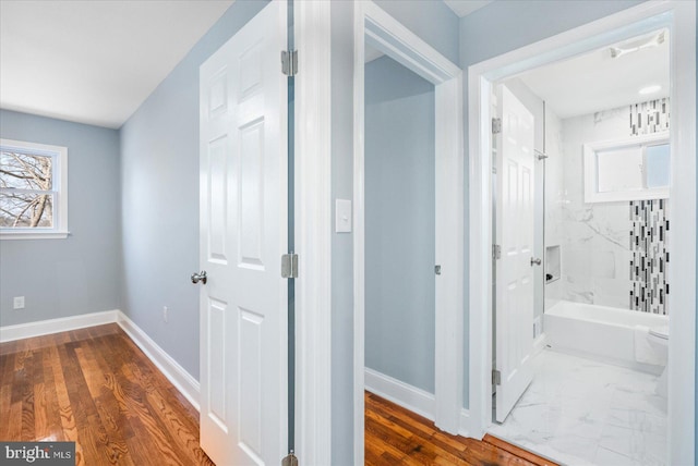 hallway featuring a healthy amount of sunlight, marble finish floor, and baseboards