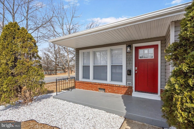 doorway to property with brick siding, crawl space, and a porch