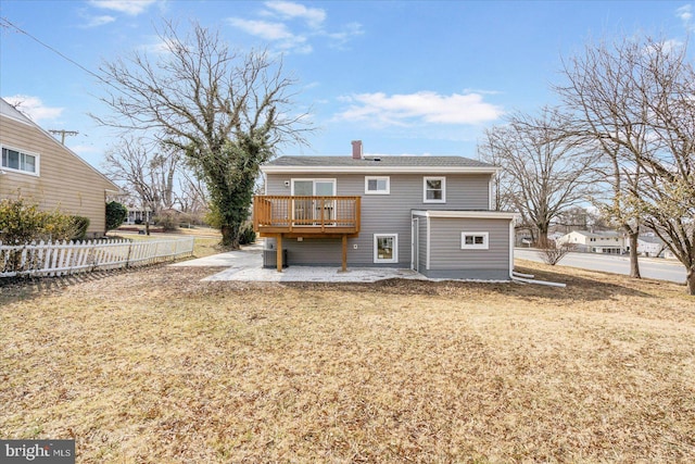 rear view of property featuring a patio, a chimney, a lawn, fence, and a wooden deck