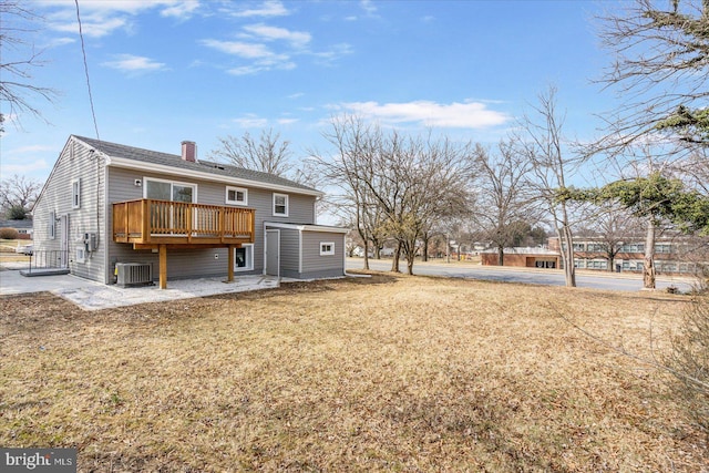 rear view of house featuring central AC unit, a chimney, a wooden deck, and a lawn