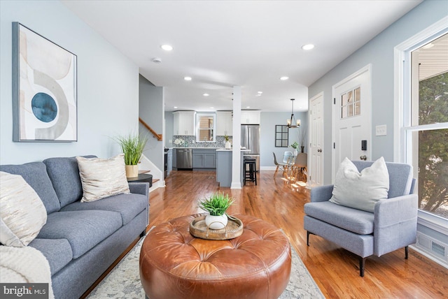 living area featuring a chandelier, recessed lighting, visible vents, stairs, and light wood-type flooring