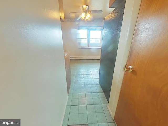 hall featuring baseboards, a baseboard heating unit, and light tile patterned flooring