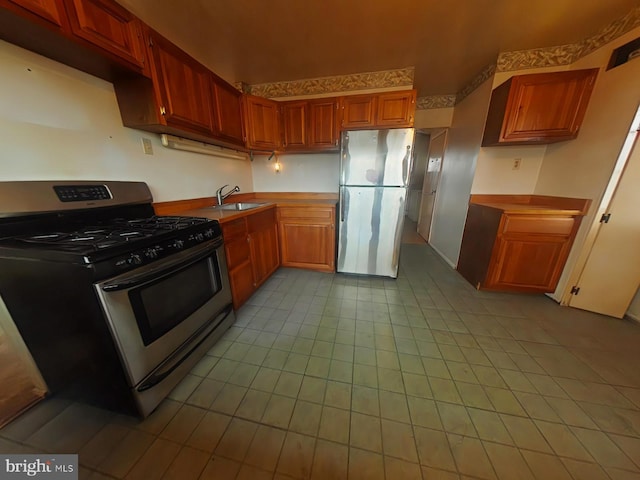 kitchen with a sink, stainless steel appliances, light countertops, and brown cabinets