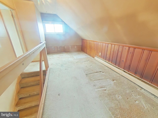 additional living space with vaulted ceiling, a baseboard heating unit, and light colored carpet