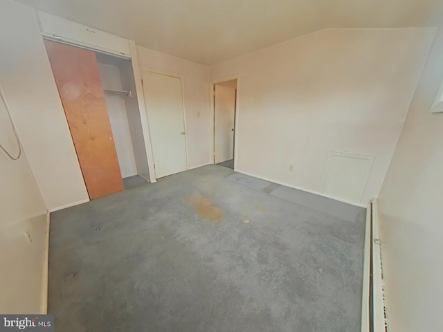 unfurnished bedroom featuring vaulted ceiling and concrete floors