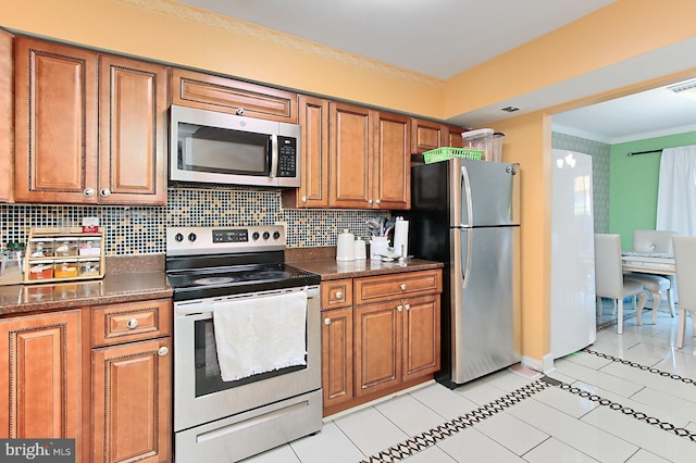 kitchen featuring ornamental molding, brown cabinets, stainless steel appliances, backsplash, and light tile patterned flooring