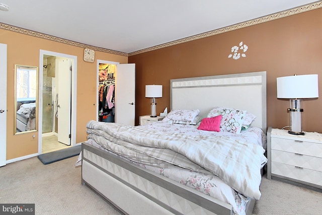 bedroom featuring light carpet, ornamental molding, ensuite bathroom, a spacious closet, and a closet