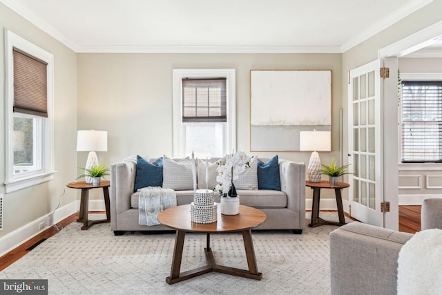 living area featuring light wood-type flooring, baseboards, and crown molding