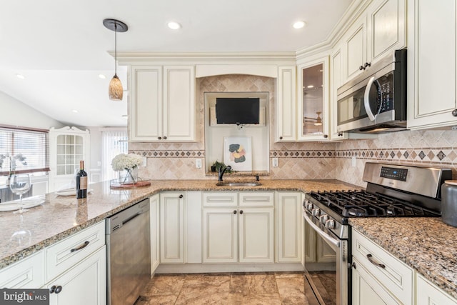 kitchen with glass insert cabinets, appliances with stainless steel finishes, light stone counters, and hanging light fixtures