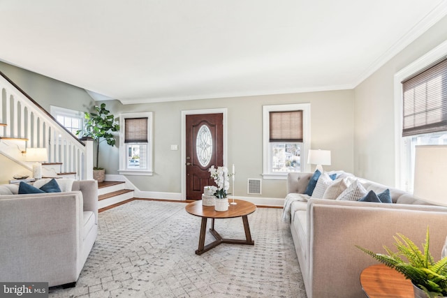 living room featuring visible vents, baseboards, stairway, light wood-type flooring, and crown molding