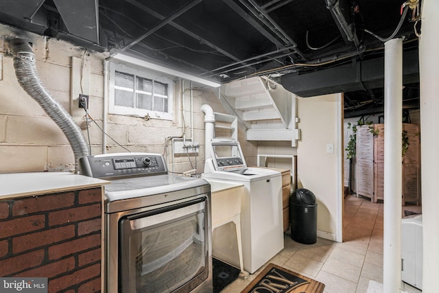 clothes washing area featuring light tile patterned floors, laundry area, and washing machine and dryer