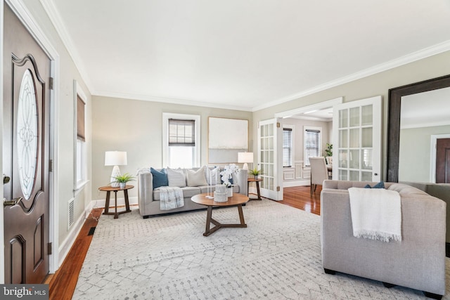 living area featuring french doors, crown molding, baseboards, and wood finished floors