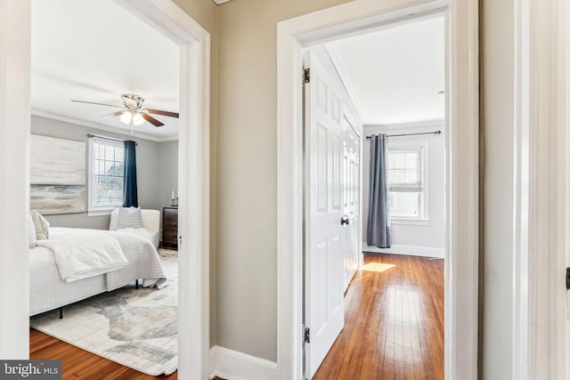 hallway with baseboards, crown molding, and wood finished floors