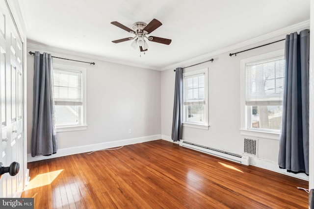 unfurnished room featuring baseboards, a baseboard heating unit, wood finished floors, and ornamental molding