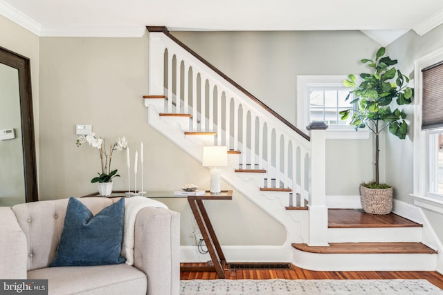 stairway with ornamental molding, vaulted ceiling, and wood finished floors