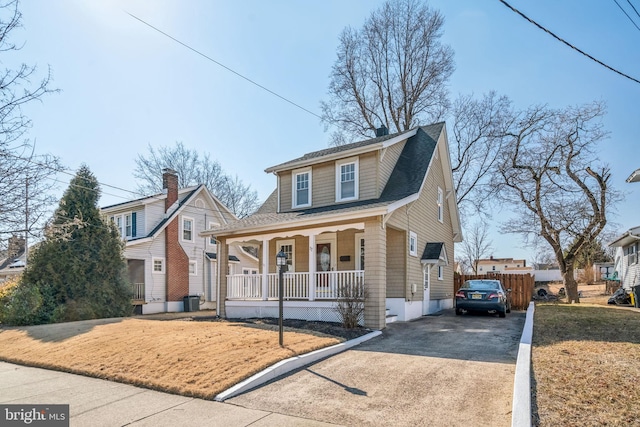 bungalow-style house featuring a shingled roof, covered porch, and driveway