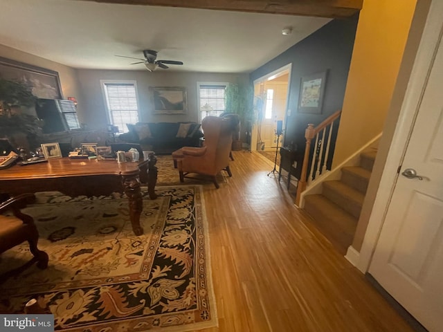 living area featuring ceiling fan, stairway, baseboards, and wood finished floors