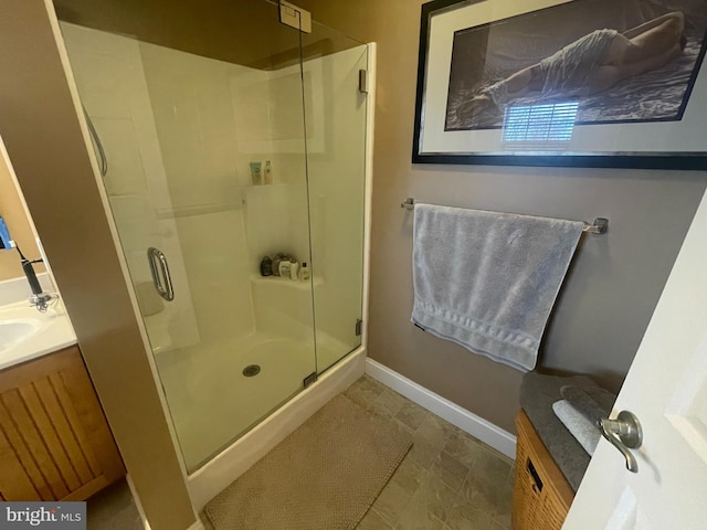 full bath featuring a shower stall, vanity, and baseboards