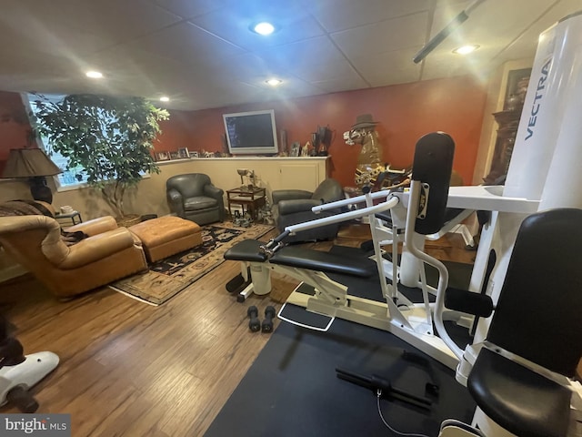 exercise room with a paneled ceiling, recessed lighting, and wood finished floors