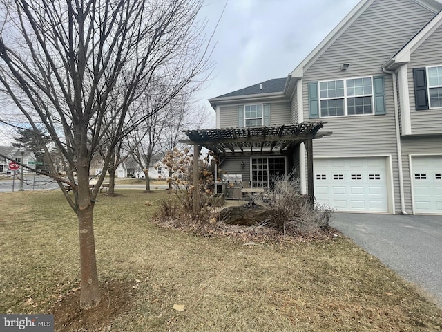 view of front of house featuring a garage, aphalt driveway, and a front lawn