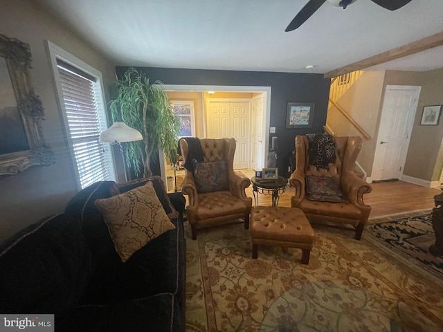 living area with stairs, wood finished floors, a ceiling fan, and baseboards