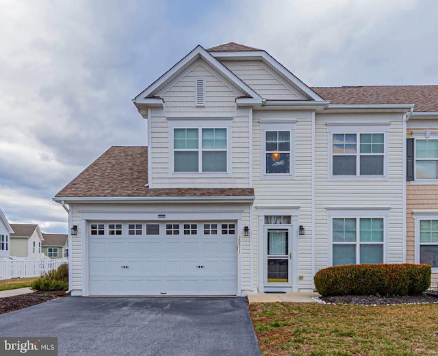 townhome / multi-family property featuring aphalt driveway, roof with shingles, an attached garage, and fence