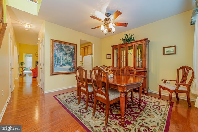 dining room featuring light wood-style flooring, baseboards, and a ceiling fan