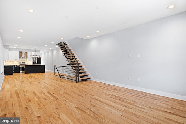 unfurnished living room featuring light wood-type flooring, recessed lighting, baseboards, and stairs