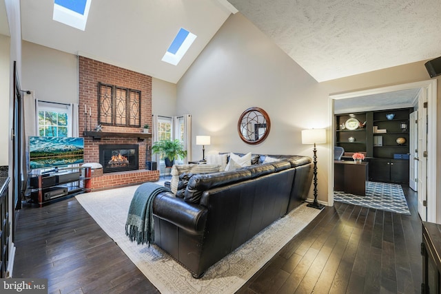 living room featuring a skylight, dark wood finished floors, a healthy amount of sunlight, a fireplace, and high vaulted ceiling