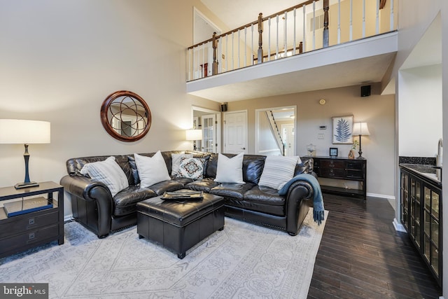 living area with a towering ceiling, baseboards, and wood finished floors