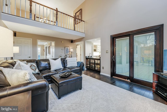 living area featuring a high ceiling, baseboards, and hardwood / wood-style flooring