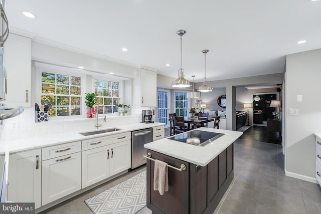 kitchen featuring decorative backsplash, black electric cooktop, stainless steel dishwasher, white cabinetry, and a sink