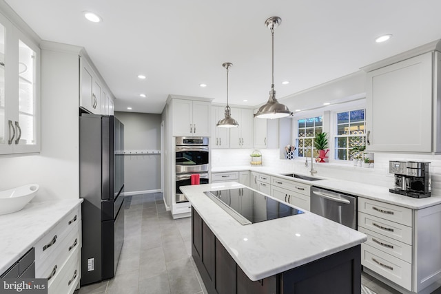 kitchen with a sink, white cabinetry, backsplash, a center island, and black appliances