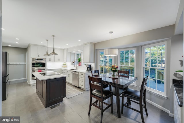 kitchen featuring light countertops, visible vents, a kitchen island, a sink, and black appliances