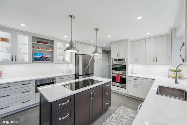 kitchen with light stone countertops, white cabinets, appliances with stainless steel finishes, a center island, and glass insert cabinets