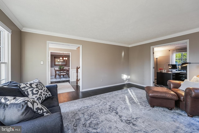 living room with hardwood / wood-style flooring, a notable chandelier, baseboards, and crown molding